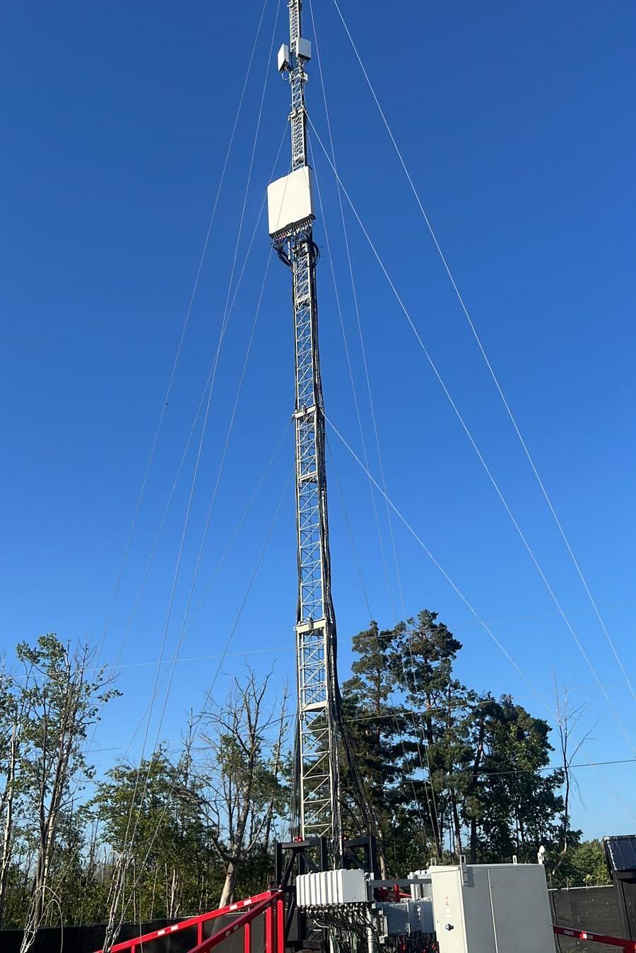 Guyed telecom tower with panel antennas and microwave dish, one of Sky Telecom Services' installed sites