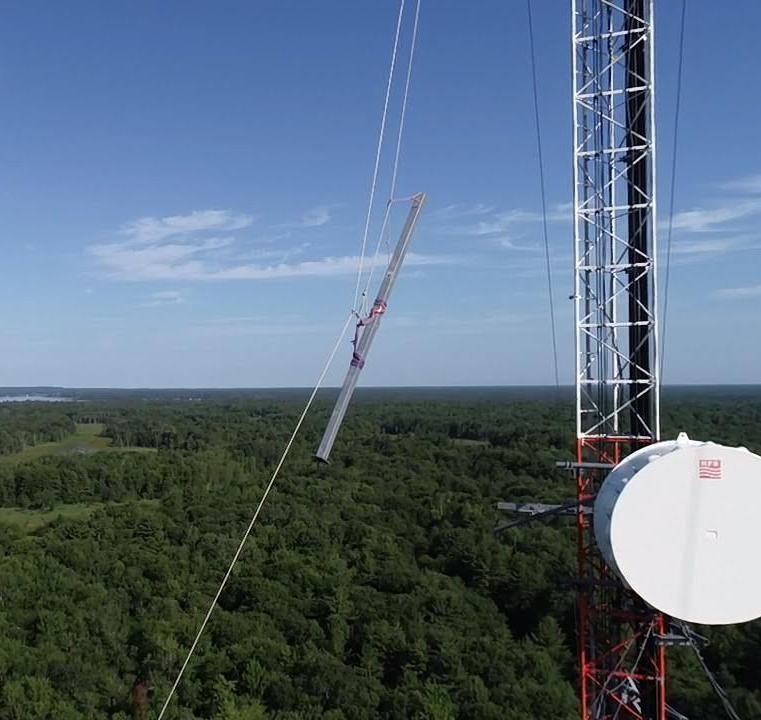 Antenna sector being hoisted up a live tower on rigging lines