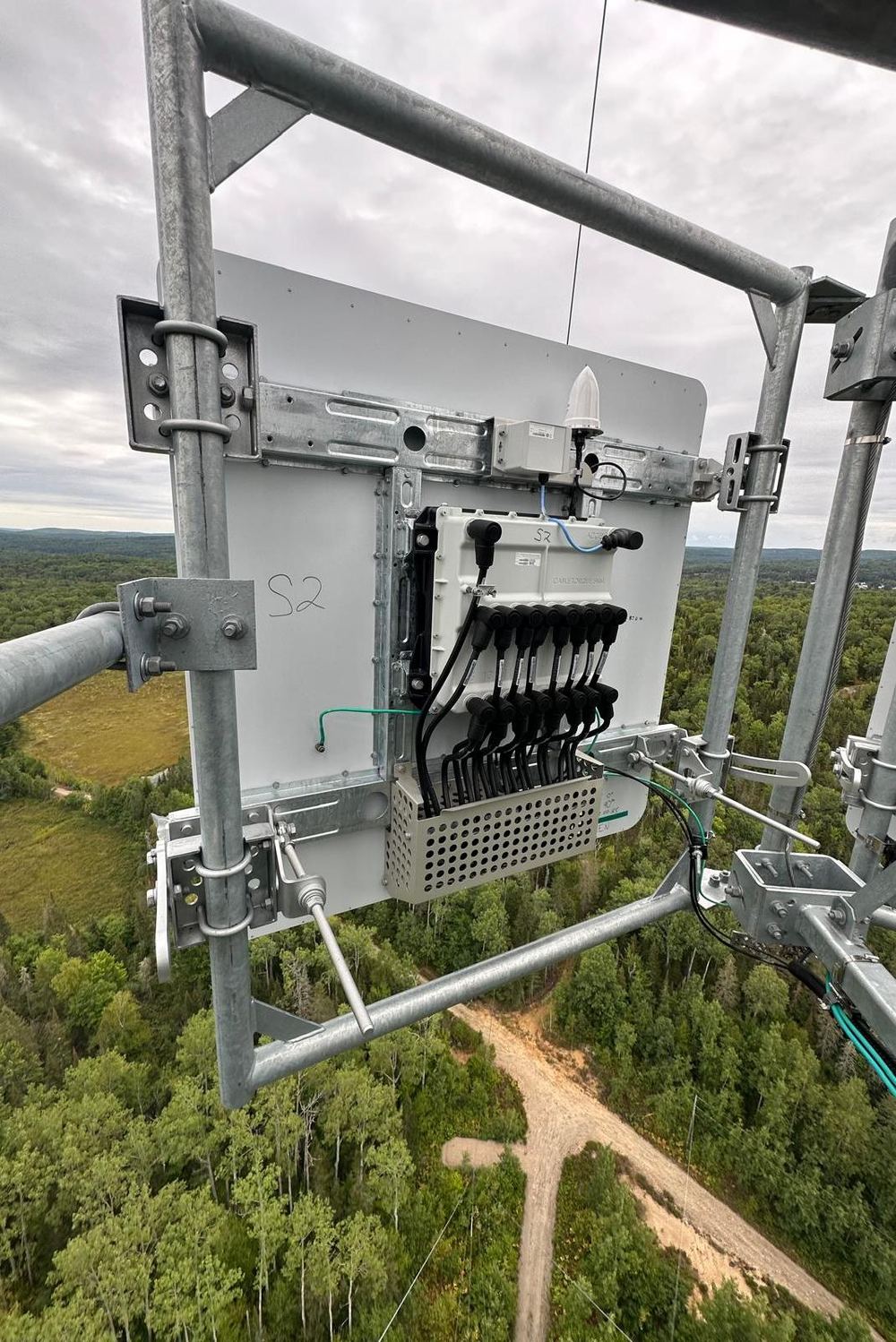 5G panel antenna and remote radio unit mounted on tower steel, overlooking forest